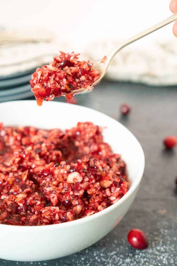 cranberry orange relish in white bowl with spoon scooping