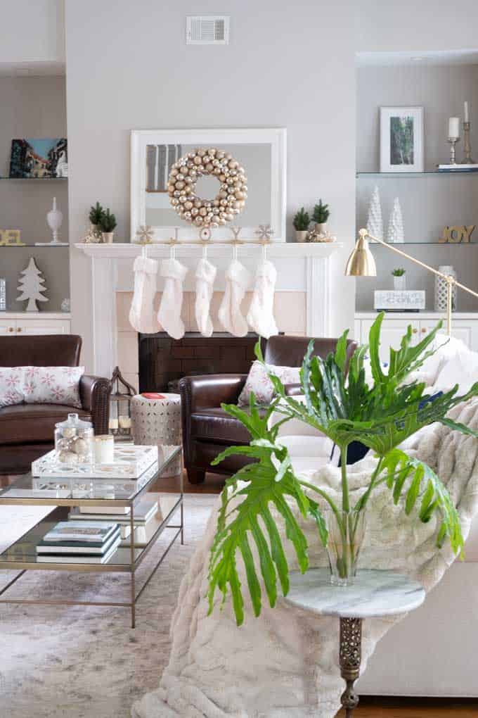 A room decorated for christmas with white stockings on fireplace.