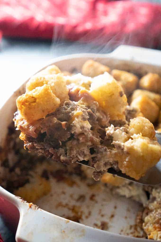 Bacon Cheeseburger Hash Brown Casserole behind scooped up from white casserole dish