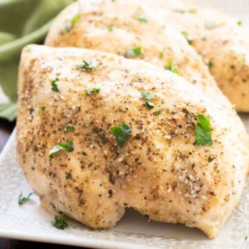 close up of baked chicken breast on white plate