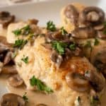 close up of chicken marsala on white plate with mushroom slices and fresh parsley on top