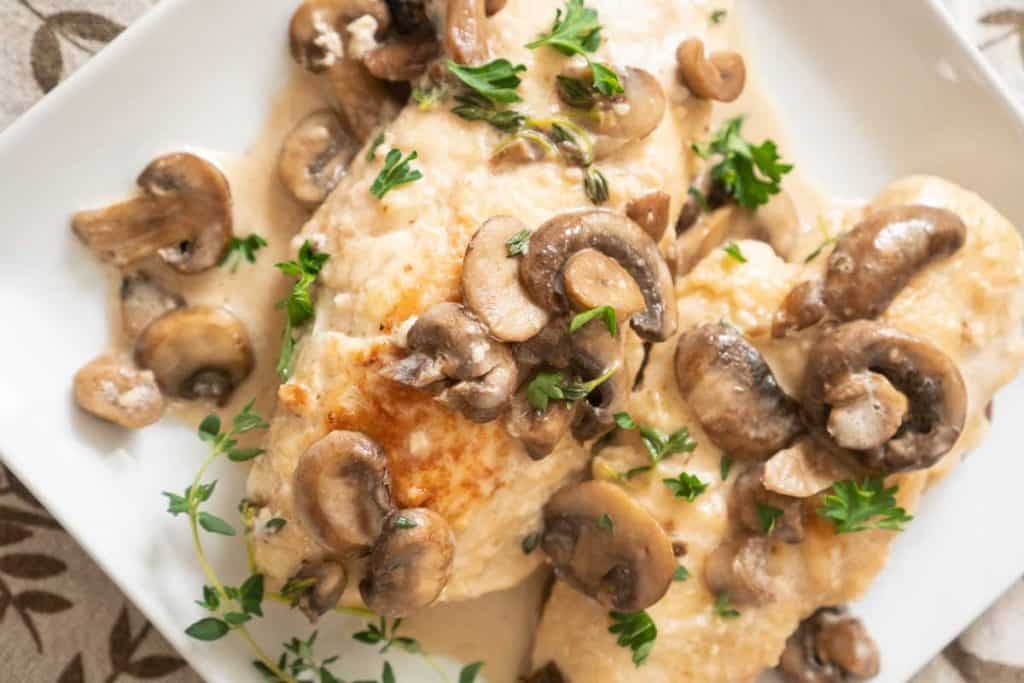  chicken marsala with mushrooms and fresh parsely on white plater from overhead