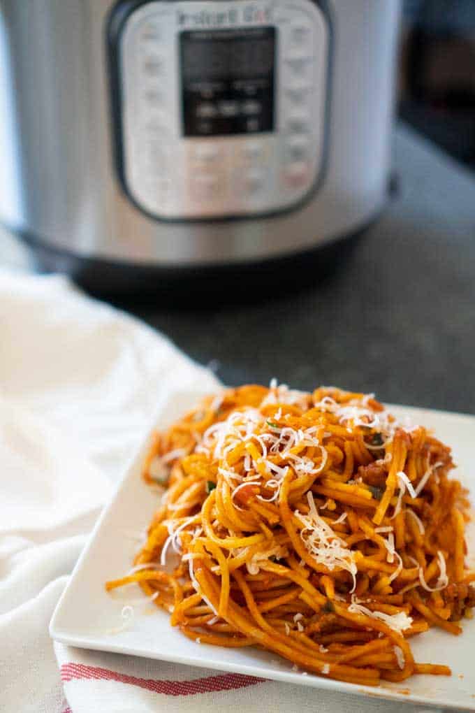 instant pot spaghetti on white square plate with instant pot in background