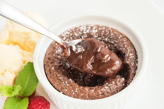 spoon scooping chocolate melting cake out of white ramekin