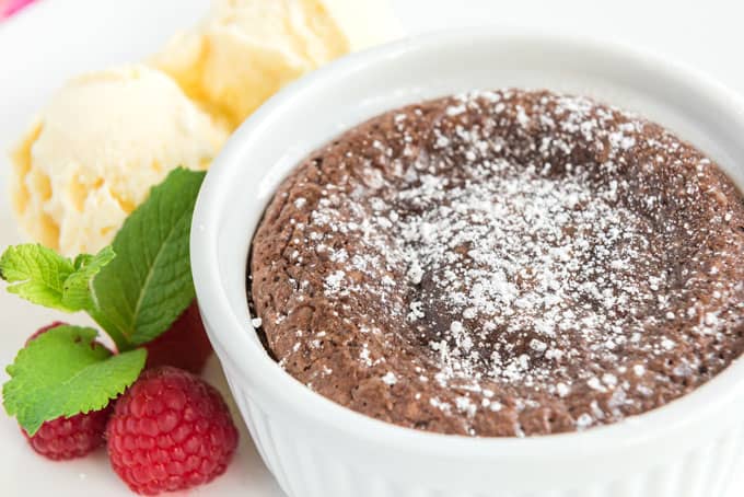 close up of chocolate melting cake dusted with powdered sugar in white ramekin
