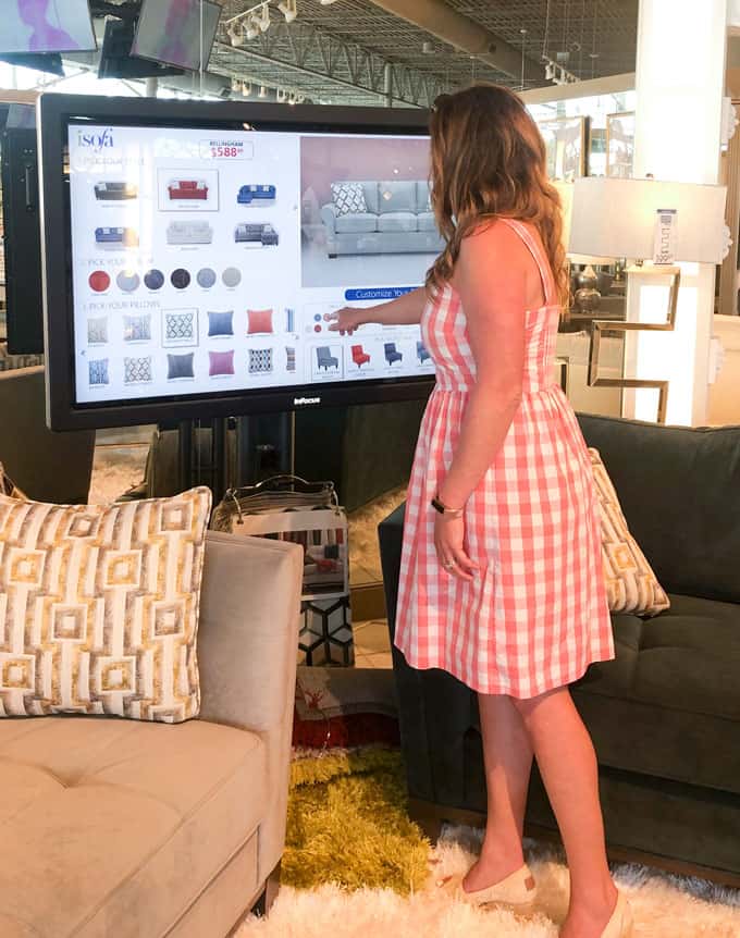 woman standing in front of touch screen isofa design center at rooms to go