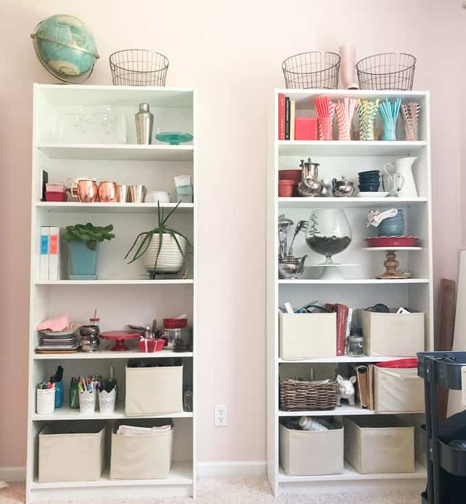 two white bookshelves with colorful craft supplies and photography props