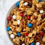 overhead view of sweet and salty snack mix in white bowl with marble background