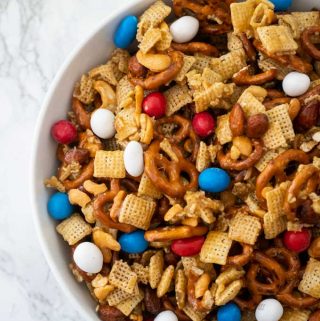 overhead view of sweet and salty snack mix in white bowl with marble background