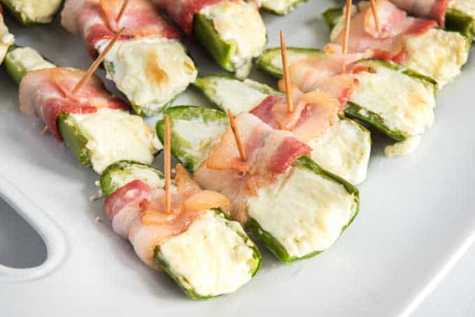 bacon wrapped jalapeño poppers on a white plate