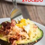 fork in a baked avocado with egg and bacon