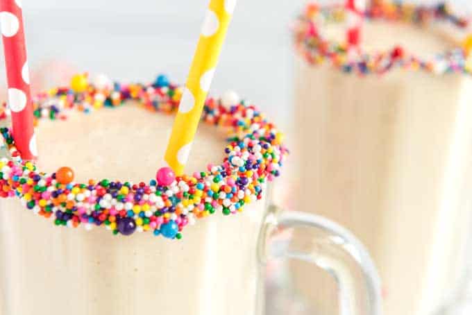 close up of cake batter smoothie timmed with sprinkles and colorful straw