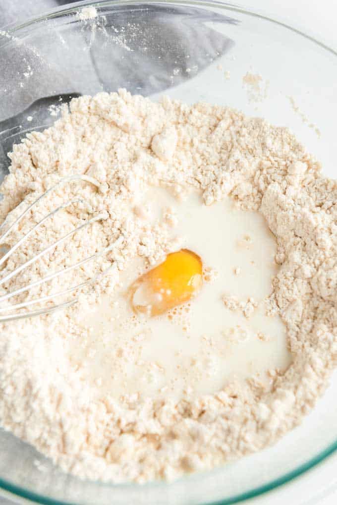 whisk stirring milk and egg into flour in glass bowl