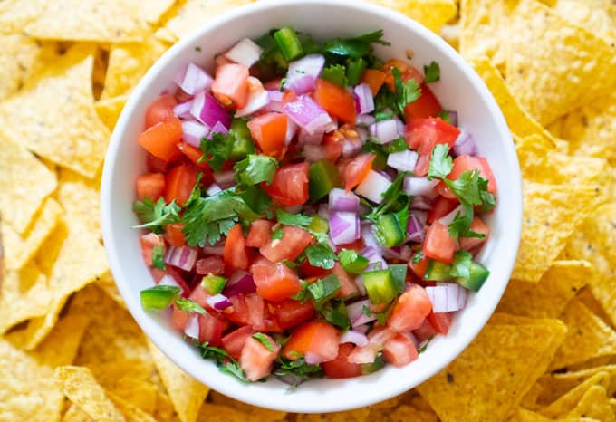 overhead view of homemade pico de gallo in white bowl with chips