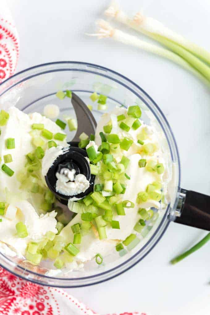 cream cheese in a food processor with diced green onions