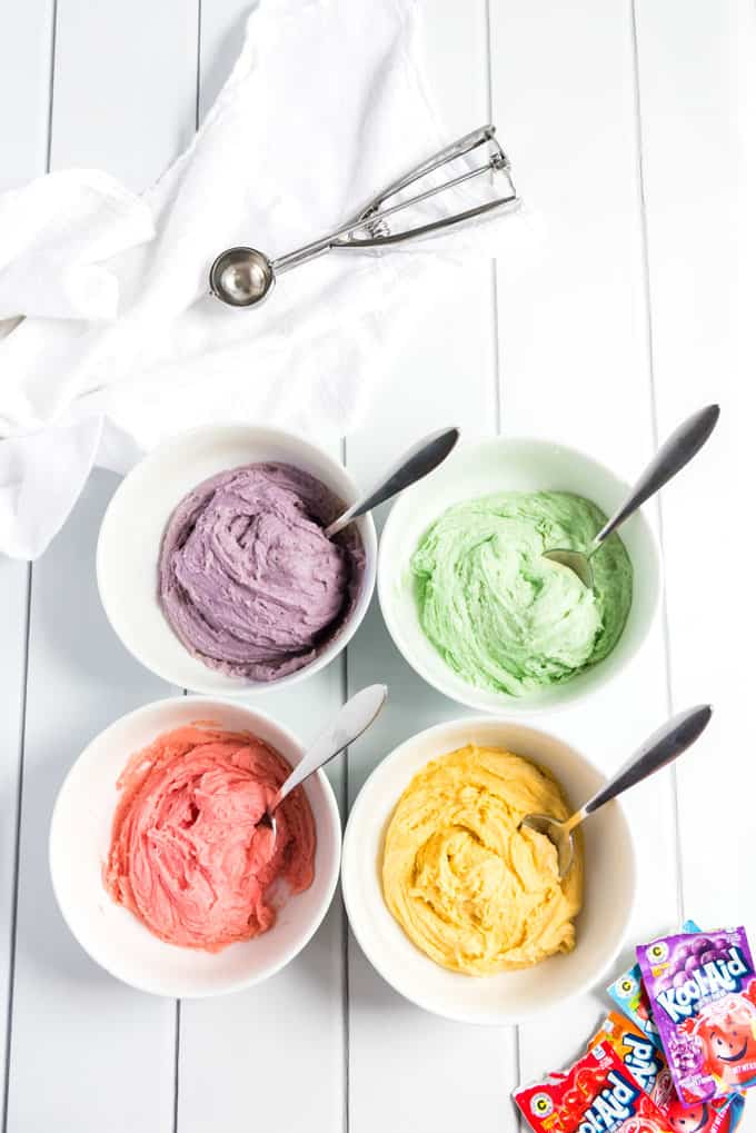 four white bowls with colorful cookie dough and cookie scoop
