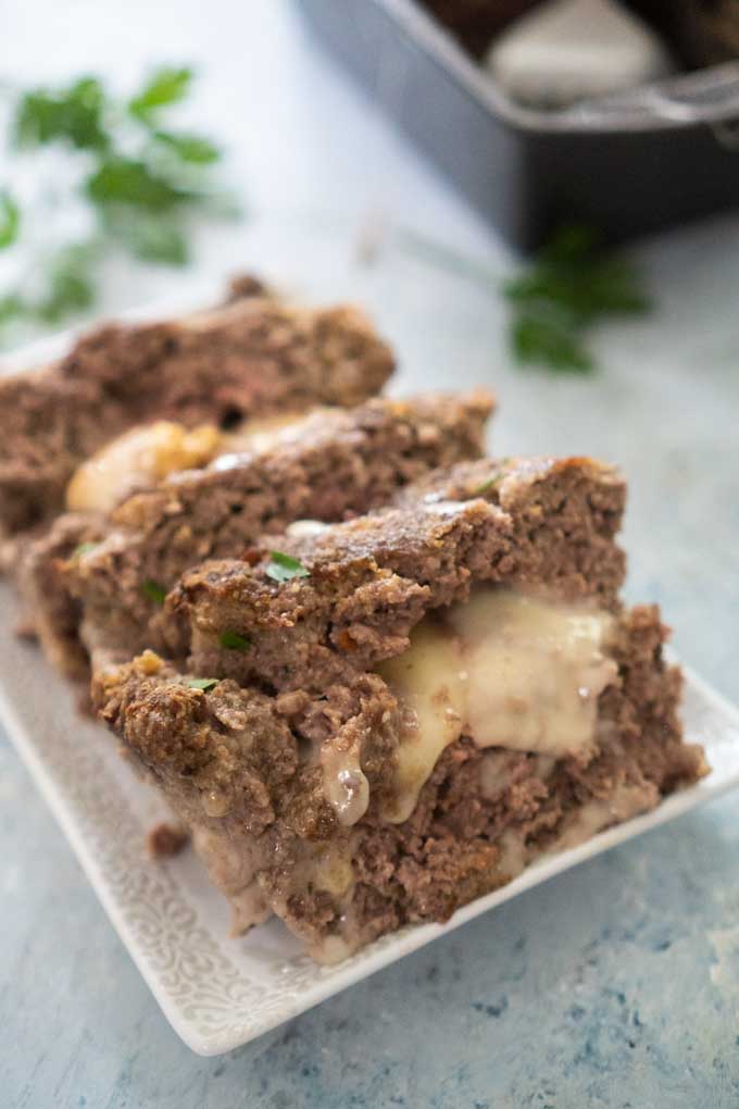 mozzarella cheese stuffed meatloaf on a white platter