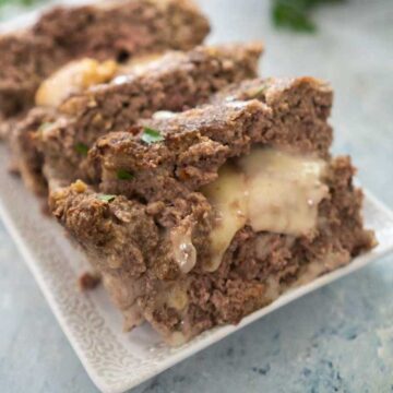 sliced cheese stuffed meatloaf on white platter