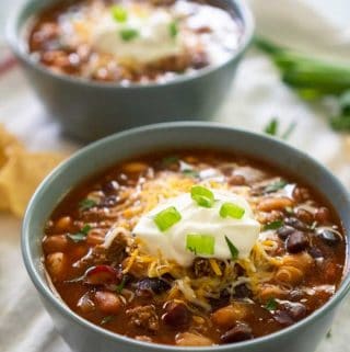 close up of Taco Soup in 2 ray ceramic bowls topped with sour cream and green onion