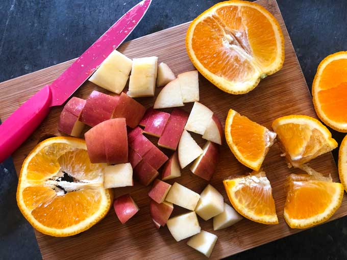 chopped apples and oranges on wood cutting board for sangria