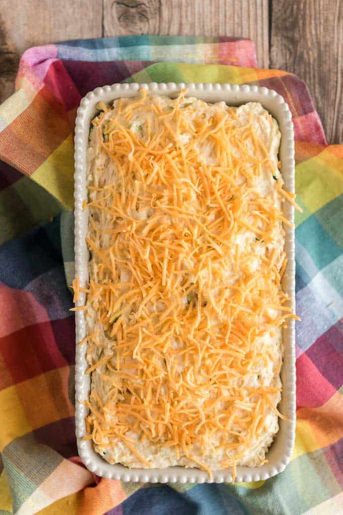 zucchini bread in loaf pan with cheddar cheese on top