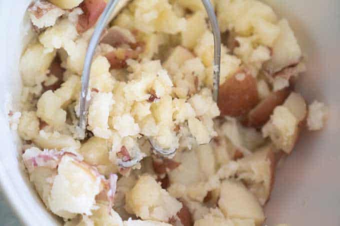 mashing potatoes to make potato salad
