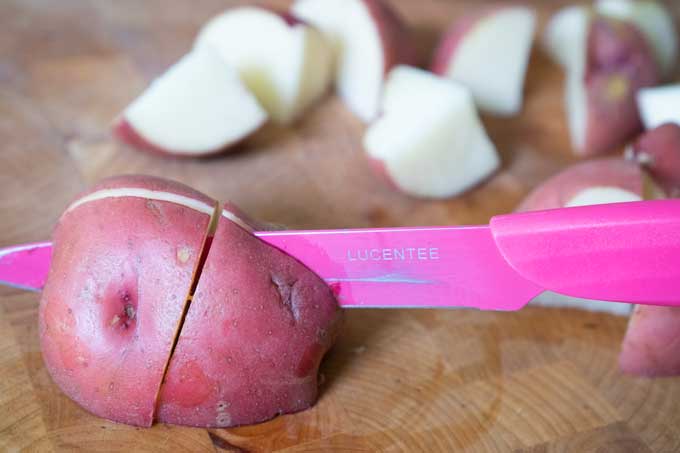 slicing potatoes to make potato salad with pink knife