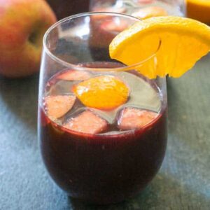 stemless wine glass with red wine sangria garnished with orange slice