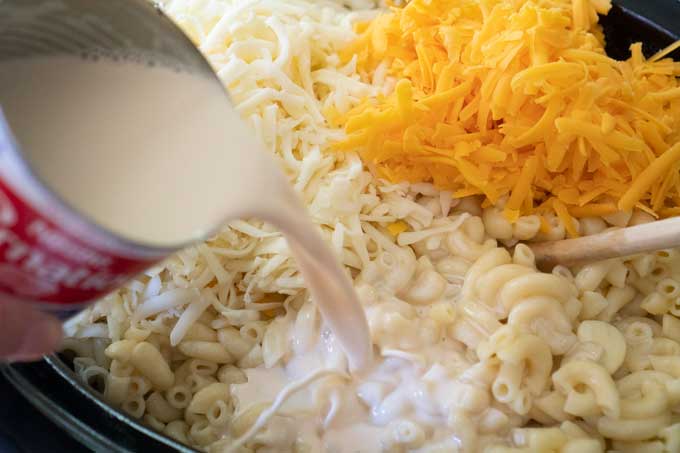 mixing elbow noodles, cheese, and milk to make slow cooker mac and cheese