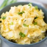 egg salad in grey bowl with chopped green onion on top