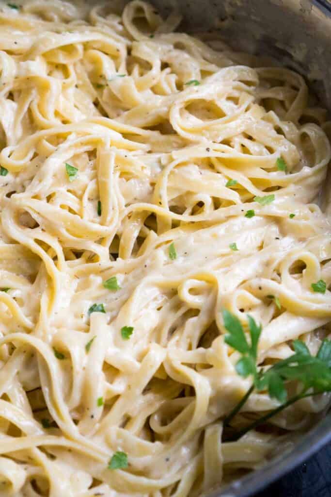 fettuccine alfredo topped with fresh parsley in skillet