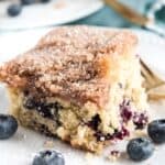 blueberry coffee cake on white plate with four blueberries