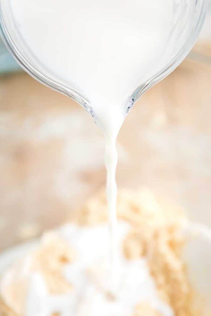 measuring cup pouring milk into coffee cake batter