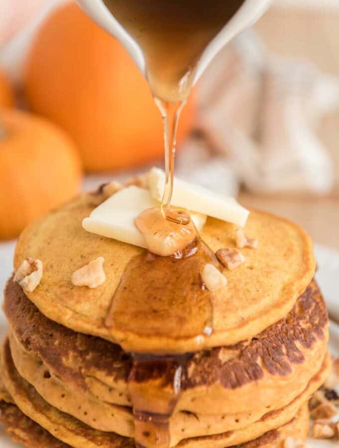 syrup pouring over stack of pumpkin pancakes