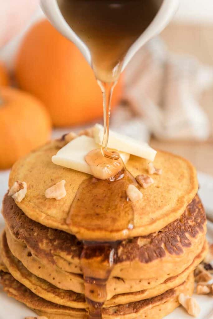 syrup pouring over stack of pumpkin pancakes