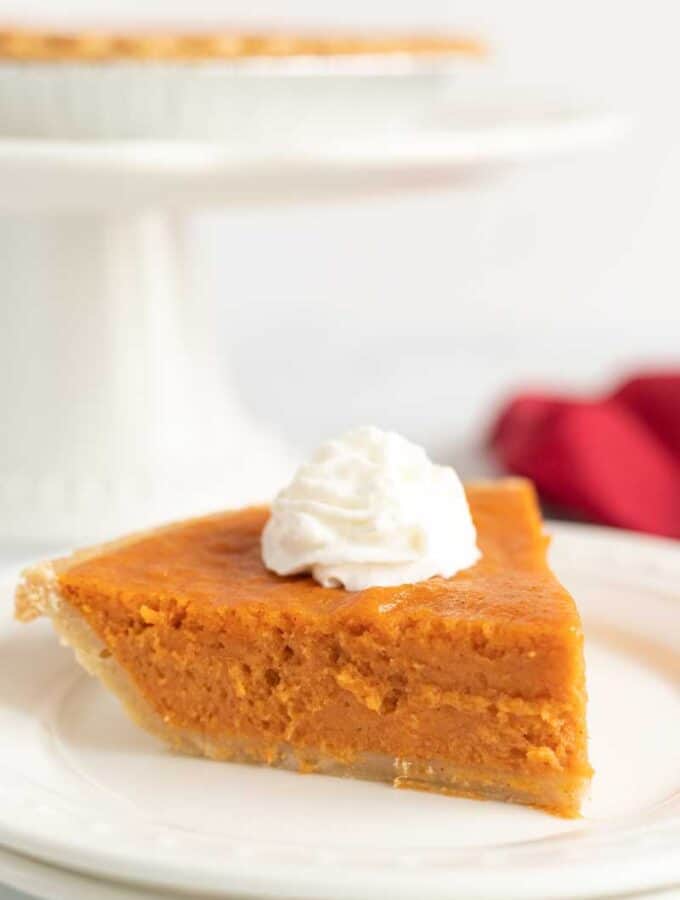 slice of sweet potato pie with whipped cream on white plate
