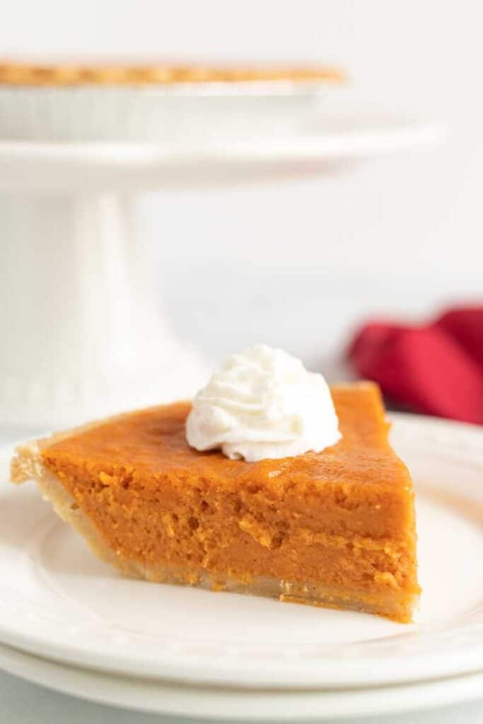 slice of sweet potato pie with whipped cream on white plate