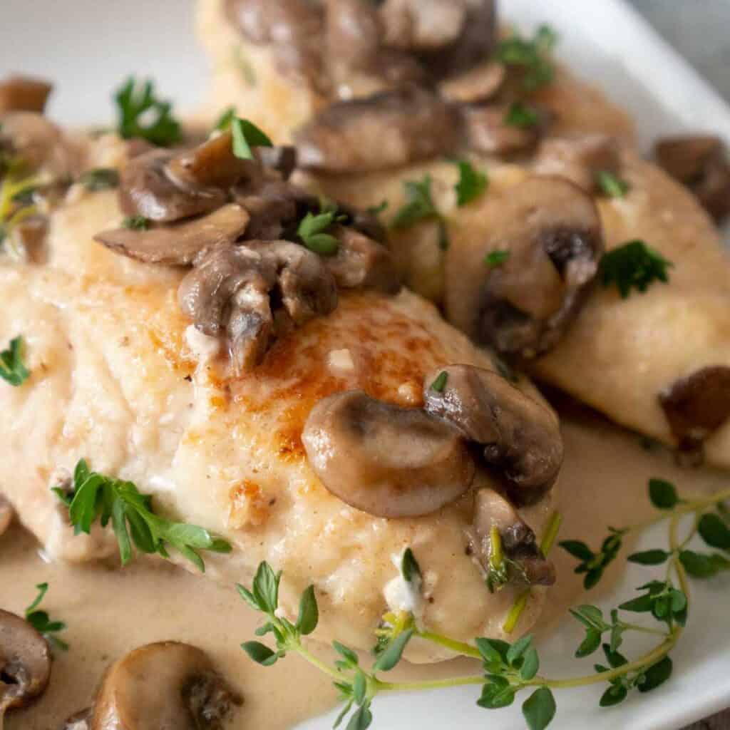 chicken marsala on white plate with thyme sprigs