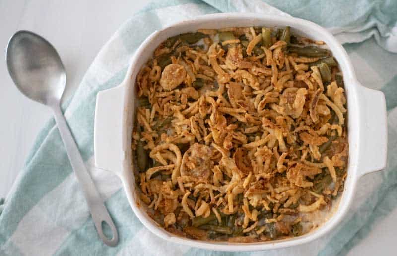 green bean casserole in a white dish with napkin and spoon