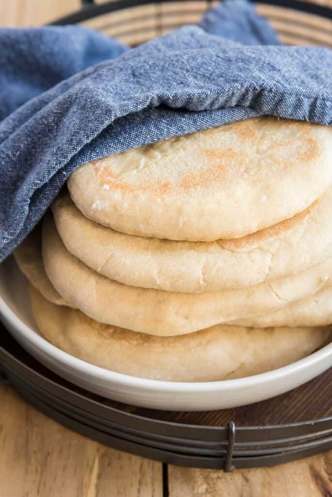 stack of homemade naan bread wrapped in blue towel