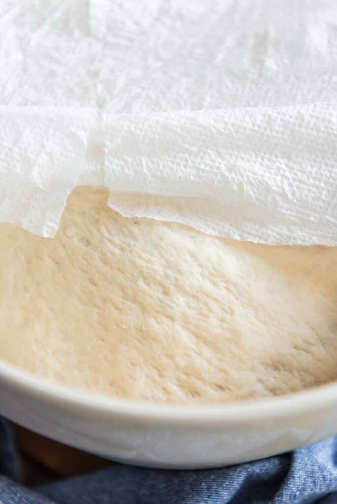 naan dough rising in a bowl covered with damp paper towel