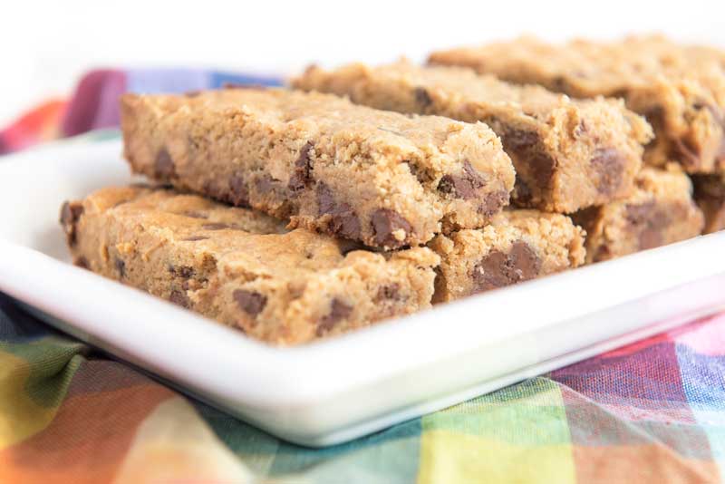 peanut butter chocolate chip cookie bars on white plate with colorful napkin 