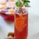 pink champagne punch in stemless flute with mint sprig garnish