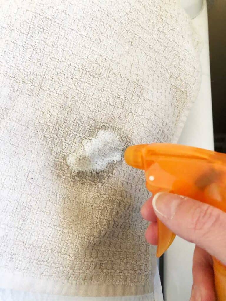 spray bottle spraying homemade stain remover on towel