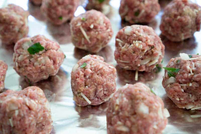 raw homemade meatballs on baking sheet lined with foil