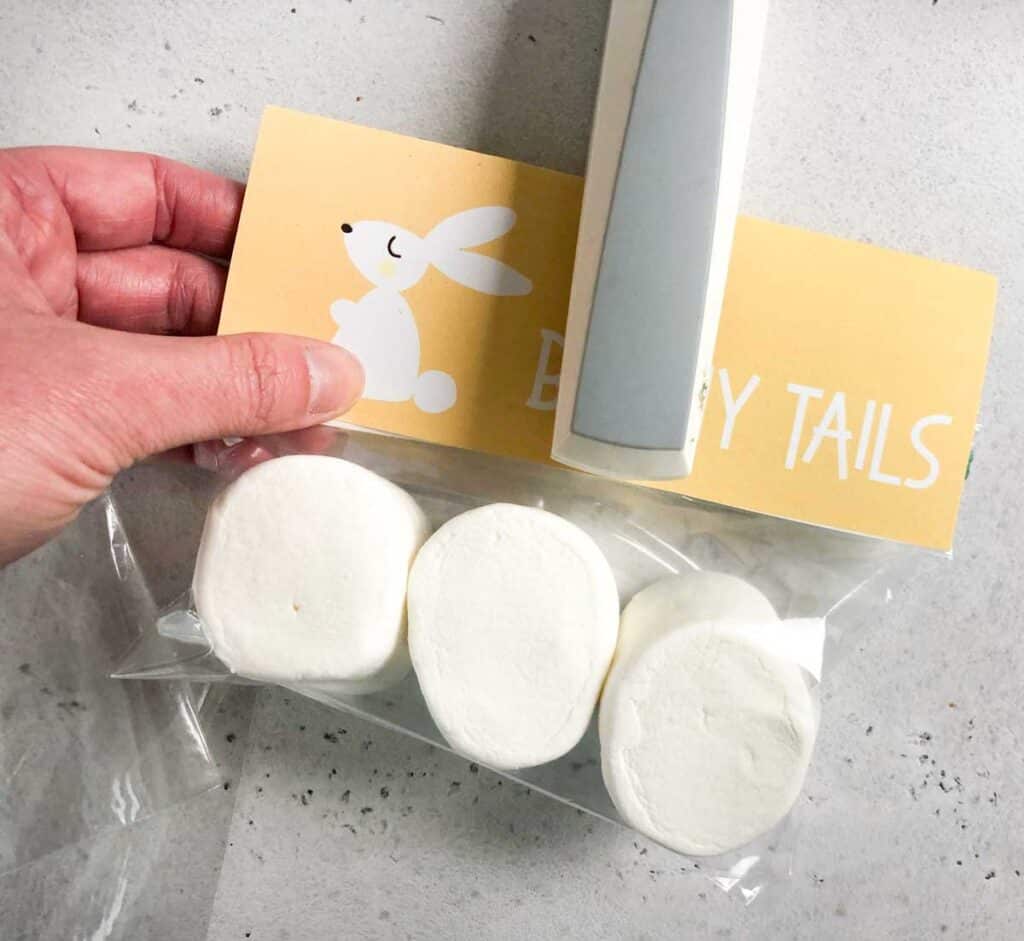 stapling free printable easter bunny tailgift tag to bag of marshmallows