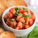 fresh bruschetta in white bowl with slices of french bread