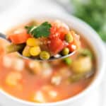 homemade vegetable soup in spoon over white bowl