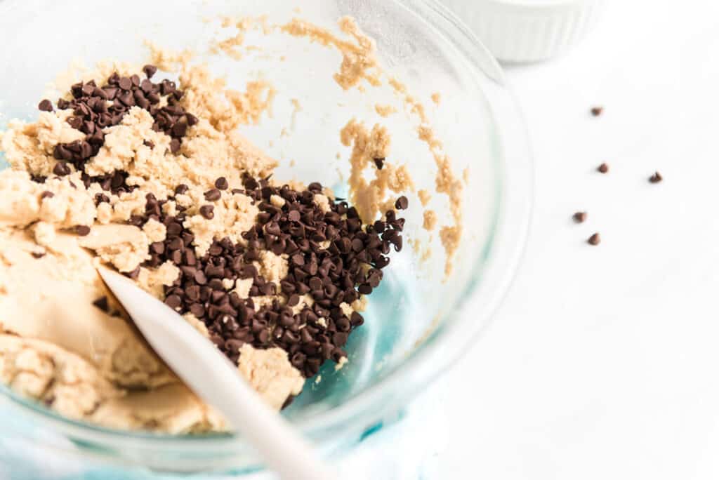 stirring chocolate chips into edible cookie dough