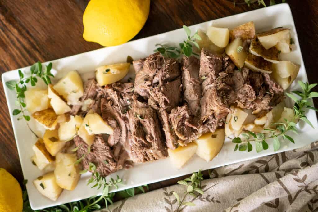 instant pot leg of lamb on white platter with potatoes